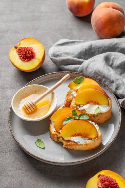 Şeftali, nektarin, krem peynir ya da ricotta ve ballı tost bruschetta taze meyve ve peçeteyle kaplanmış koyu bir tabakta. Sağlıklı yaz atıştırmalığı konsepti. Üst görünüm, alanı kopyala.