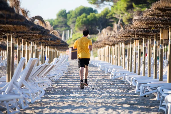 Unrecognizable runner on beach between sunbeds — Stock Photo, Image