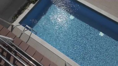 Açık havuzun mavi suyunu sürekli olarak yukarıdan değiştiriyor. Güneşli bir günde güzel dalgalı su yüzeyinin yavaş hareket etmesi. Sakin ve meditasyon tatili.