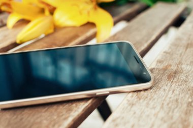 Vintage grunge ahşap masa, boş ekran, üzerine düşünceler ile akıllı telefon closeup görünümü arka planda sarı çiçekler bulanık. Hediyelik konsepti