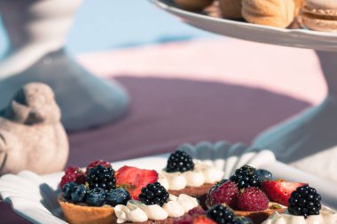 Lezzetli tatlı büfesi ile cupcakes, çilek, kurabiye ve diğer tatlılar. Düğün ya da olay dekorasyon tablo ayarı mavi renklerde. Açık havada yaz saati. Lüks yemek kavramı