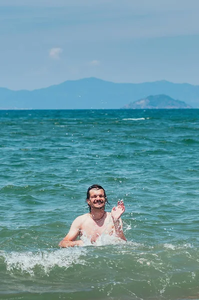 Hombre Guapo Divirtiéndose Mar Salpicando Agua Alrededor Linda Sonrisa Concepto —  Fotos de Stock