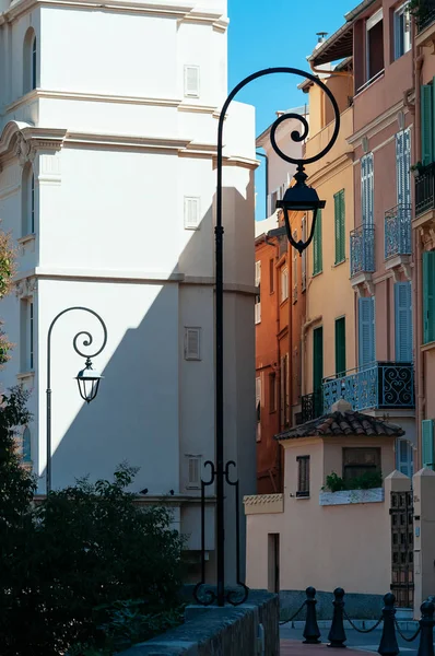 Iron Lantern lights beautifully curved, Monaco streets, sunny day. Narrow street with cute colored walls and windows. Travel Europe