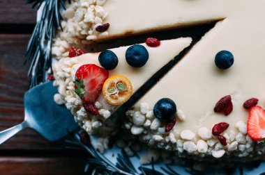 Üstten görünüm portre pasta beyaz çikolata sosu ile taze çilek, yaban mersini, goji, limon ve biberiye, kahverengi ahşap masa arka plan ile dekore edilmiştir. Seçici odak. Görüntü menüsü veya şekerleme kataloğu için