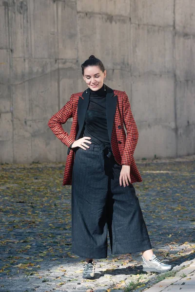 Street style Fashion portrait charming young woman in trendy clothes. Black blouse and trousers, tile red plaid jacket, silver shoes. Spring Autumn collection classic to casual look