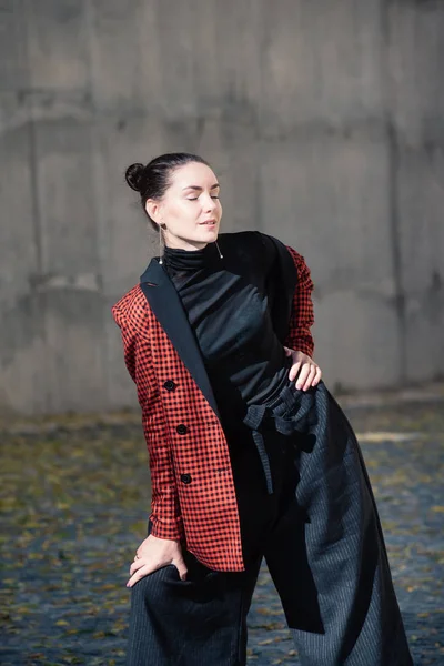 Street style Fashion portrait charming young woman in trendy clothes, eyes closed. Black blouse and trousers, tile red plaid jacket, silver shoes. Spring Autumn collection classic to casual look