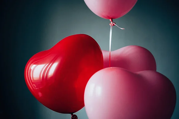 Sweet love Valentines romantic concept. Vintage red pink balloons heart shape flying up against pastel grey backdrop. Film grain effect, Soft selective focus close up image