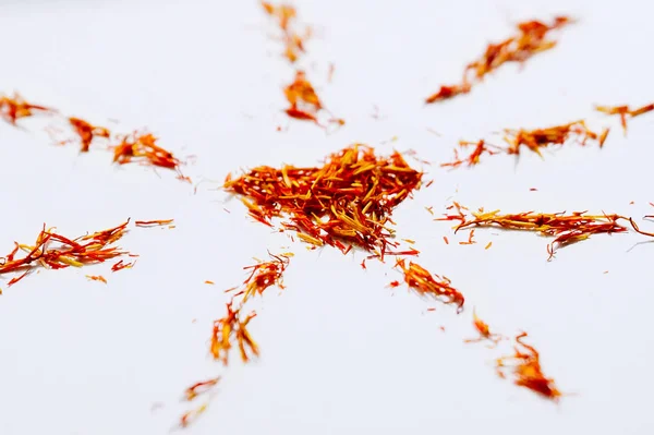 Selective focus close up Red Saffron in shape of mandala with heart on white background. Delicate flower threads. Natural healthy spice. For cafe menu or catalog