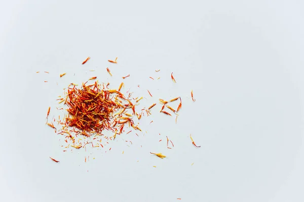 Red Saffron on white background. Delicate flower threads, plucked from flowers and dried. Top view of natural healthy spice. Copy space for text and design