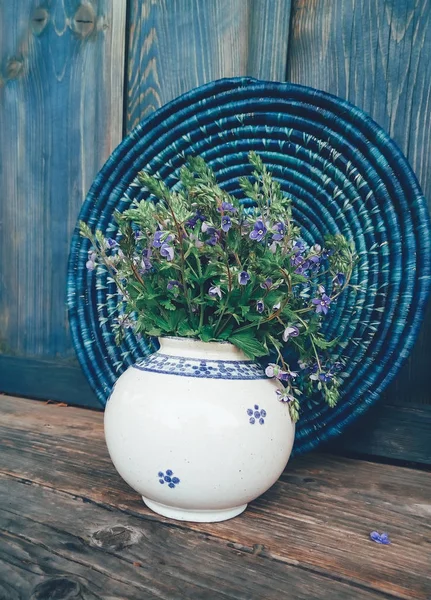 Blue field flowers in vase on wooden background