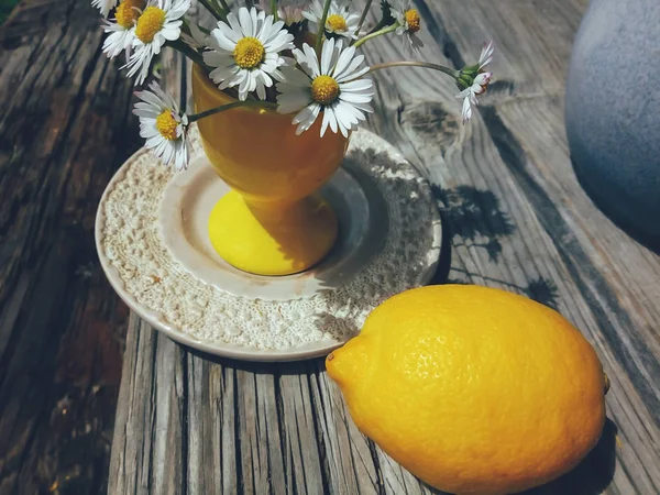Blumen in gelber Vase und Zitrone Stockbild