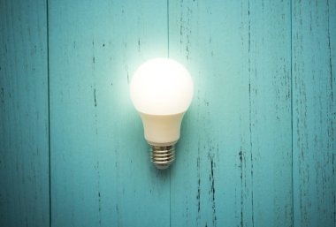 Eski püskü ahşap arka plan üzerinde LED ampul.