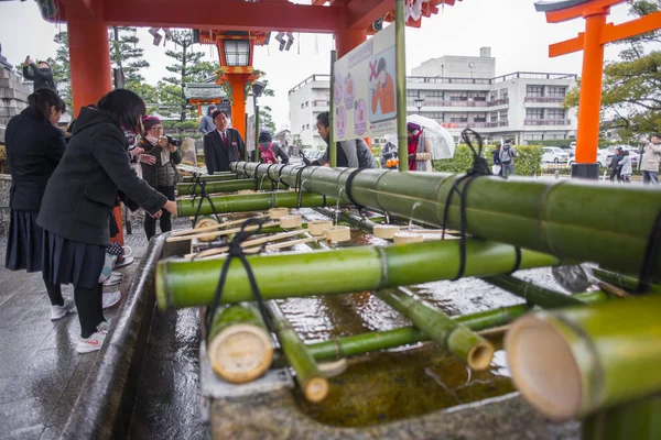 Kyoto, Japonya - 09 Şubat 2017: Ağız ve el yıkama kova tapınak veya Tapınağı önünde kullanan kişiler.