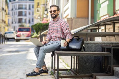 Kişisel connnection. Açık havada kahve içerken dizüstü bilgisayar kullanarak Neşeli erkek serbest