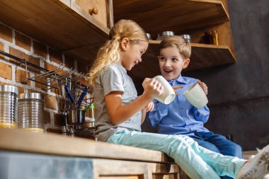 Neşeyle dolu. Çay içerken mutfakta oturan neşeli mutlu kardeşler