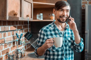 Hoş bir konuşma. Neşeli pozitif güzel adam gülümseyen ve telefonda arkadaşı ile konuşurken çay içerken