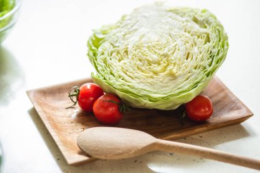 Tahta kaşık ve kiraz domates ile taze lahana ile dikdörtgen ahşap plaka yakın