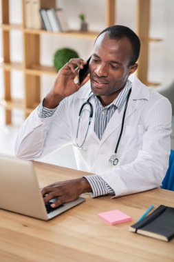 Bilgileri kontrol ediyorum. Yakışıklı uluslararası doktor onun bilgisayar ile çalışırken telefon başına konuşuyor