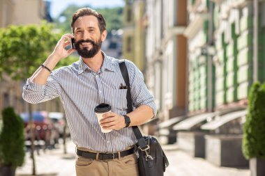Günlük alışkanlık. Neşeli yakışıklı adam sabah telefonda konuşurken kahve içme