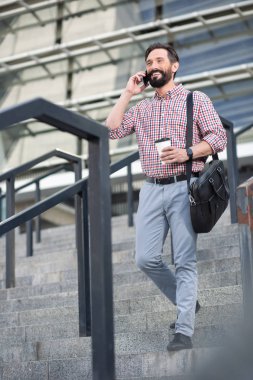 Merdivenlerden inerken telefonda konuşan neşeli yakışıklı adam