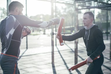 Profesyonel Mma boksör onun eğitmen ile açık havada olmak ve boks sopaları üzerinde yumruklar mastering