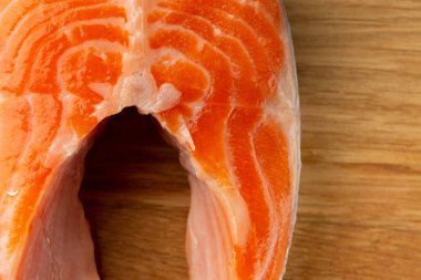 Ahşap yüzeyde yatan bir parça ham kırmızı somonun yakın fotoğrafı