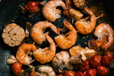 Sarımsak ve domates ile kızartma tavası üzerine yerleştirilen gevrek kabuk ile karides şiş üst görünümü