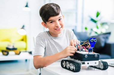Derslere hazırlanırken modern robot yapan hoş ve gülümseyen bir çocuğun bel
