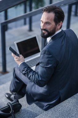 Kentsel zihniyet. Neşeli profesyonel busnessman onun modern cihazlar açık havada kullanarak