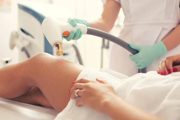 Close up photo of the modern laser tool in the hand of professional specialist during the procedure of laser stretch mark removal