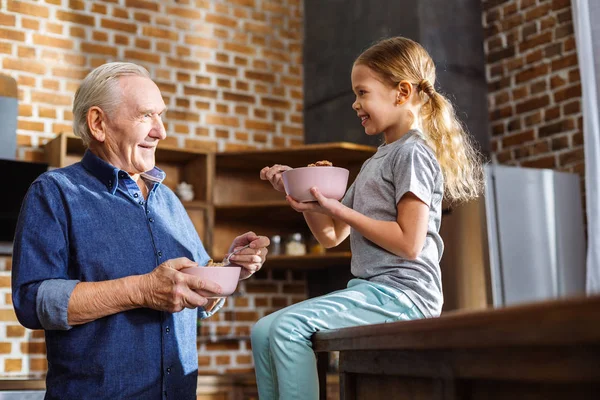 Próbálja Vidám Kislány Élvezi Reggelizni Miközben Beszélt Nagyapja — Stock Fotó