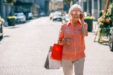 Şık yaşlı kadın telefonda konuşuyor ve mutlu görünümlü
