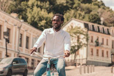 Pozitif genç adam gülümseyen ve sokakta bisikletsürme