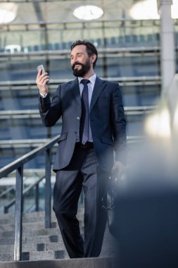 Her gün rota. İşe giderken telefonunu tutan gülümseyen işadamı mutlu