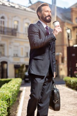 Kariyer hakkında düşünceler. Profesyonel yakışıklı işadamı açık havada dururken kahve içiyor