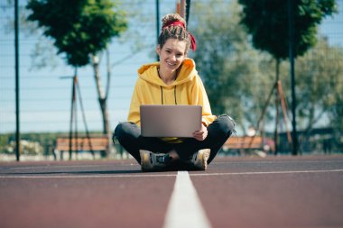 Dreadlocks gülümseyen ve yerde onu modern dizüstü bilgisayar ile otururken mutlu görünümlü güzel rahat genç bayan