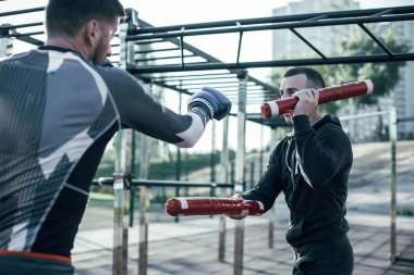 Mma şampiyonu özel boks sopaları tutan antrenörü ise onun yumruklar ustalaşma