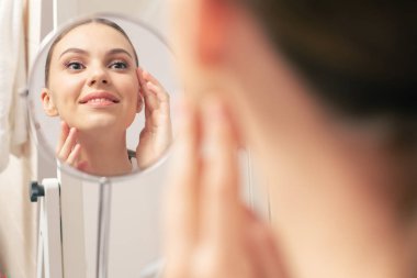 Yuvarlak ayna ve içinde olumlu genç gülümseyen kadının yansıması yakın