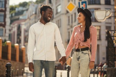 Neşeli genç adam onun güzel kız arkadaşı ile el ele tutuşarak açık havada ve gülüyor