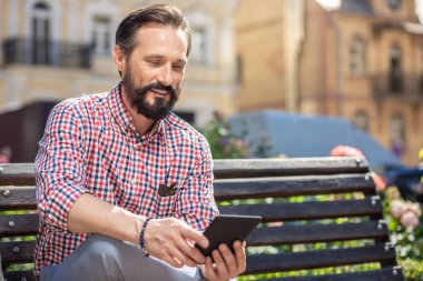 İyi bir ruh halinde. Yedek kulübesinde otururken e-kitap kullanarak Joyful yetişkin adam