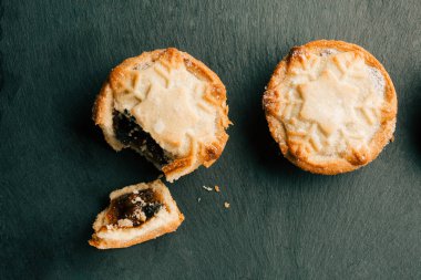 Siyah kayrak yüzeyinde yaban mersini reçeli dolum ile iki Noel kıyma turta üst görünümü