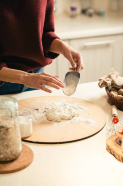 Mutfakta yemek pişiren ve hamurun üzerine un emerek genç kadının elleri