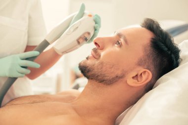 Fotoğraf gençleştirme için modern bir araç tutarak sağlık çalışanı ise sakin genç sakallı adam gülümseyen