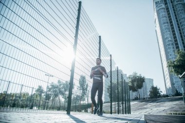 Kendine güvenen sakallı sporcu spor sahasında olmak ve zincir bağlantı çit yakınında çalışan