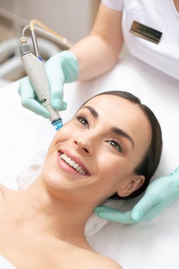 Profesyonel klinikte yüz derisinin dermabrazyonuna sahip pozitif koyu saçlı kadının yakın lığı