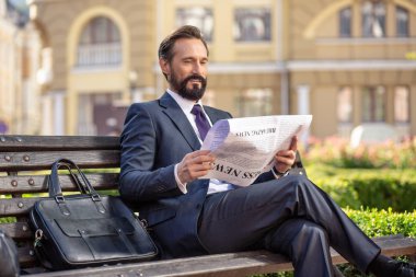 Daha fazla bilgi alın. Hoş konsantre işadamı bankta otururken gazete okuyor