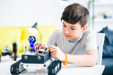 Usta konsantre öğrenci mühendislik projesini hazırlarken robotik cihazını inşa ediyor