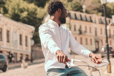 Şehirde güneşli bir günde neşeli adam bisiklet