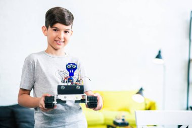 Mühendislik yarışmasına hazırlanırken bir robot tutan neşeli güzel küçük çocuk