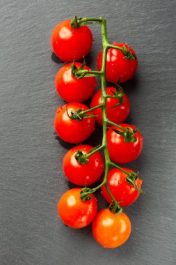 Üzerinde kiraz domates ıslak olgun dalı ile siyah kayrak yüzeyinin üst görünümü